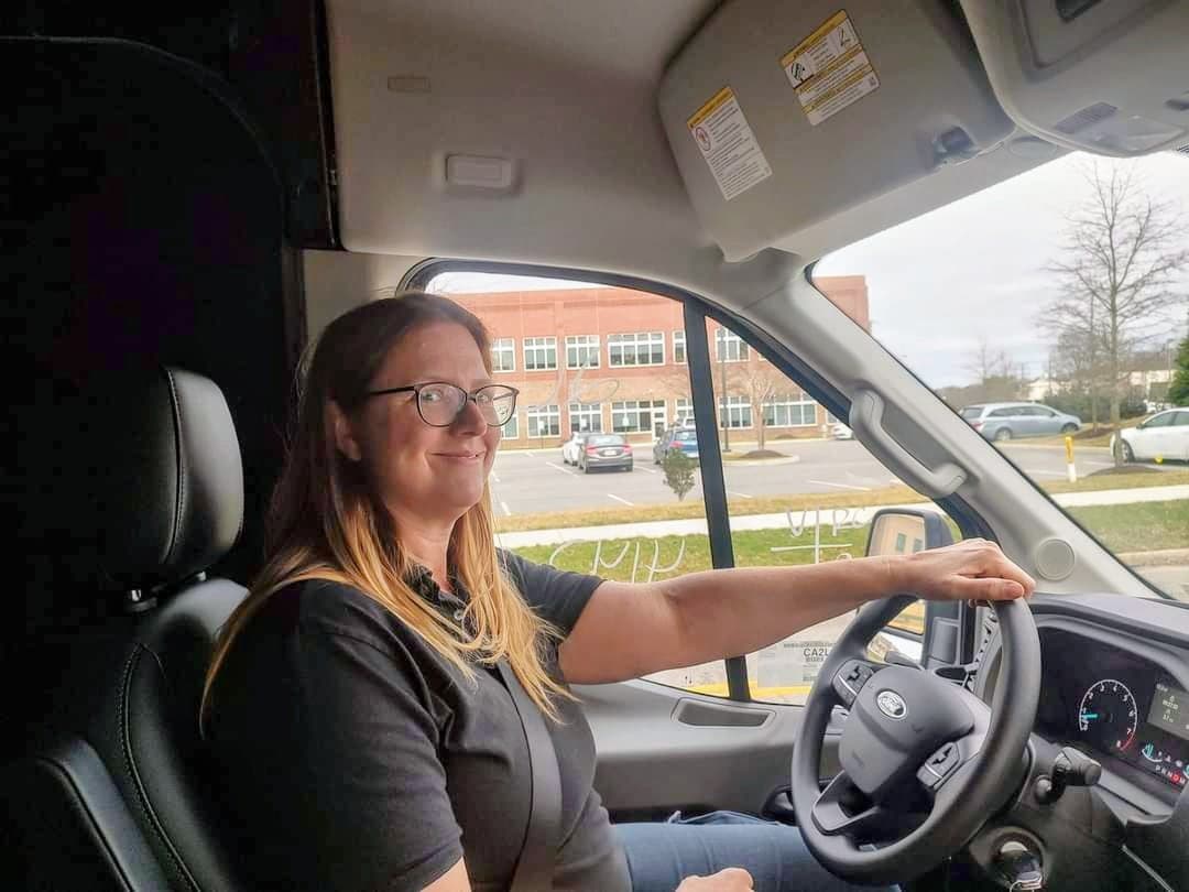 Mary Petrone, owner of Petrone Locksmith, smiling from the driver's seat of her service vehicle