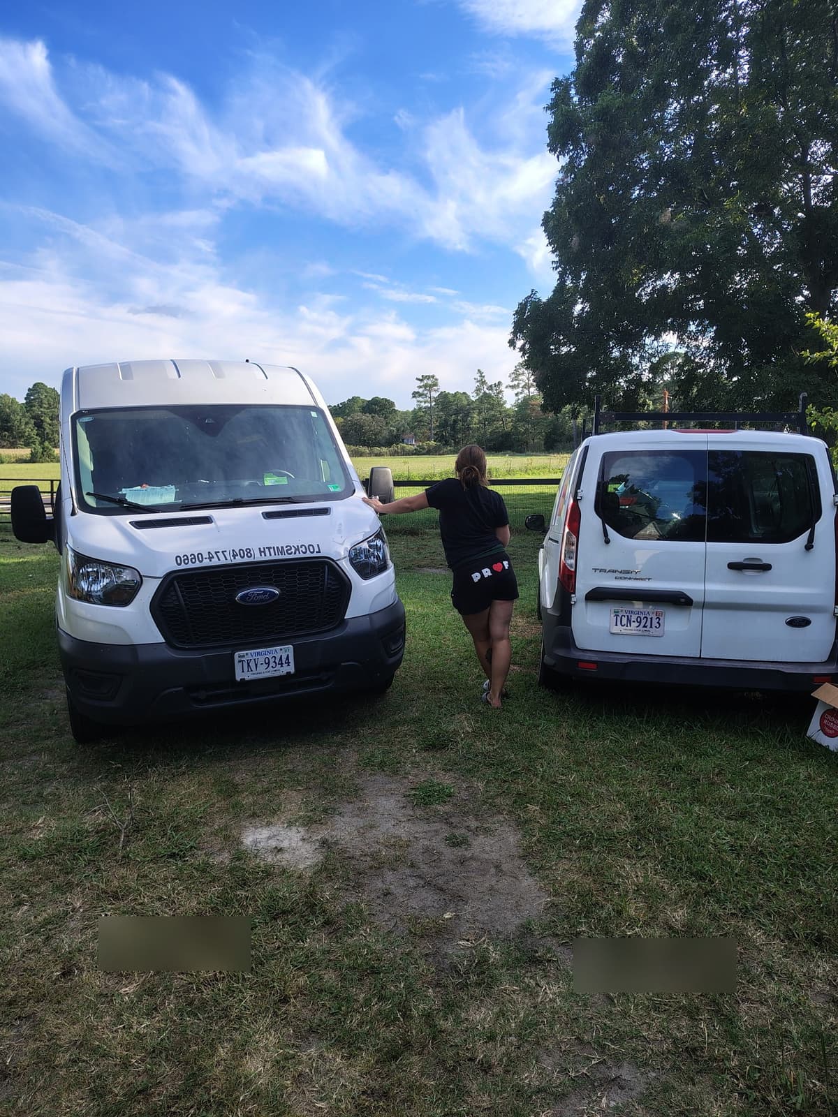 Mary Petrone standing between two Petrone Locksmith service vans in Richmond, Virginia